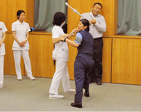 藤枝警察署の人から職員が傘を使った防犯訓練の指示を受けている写真