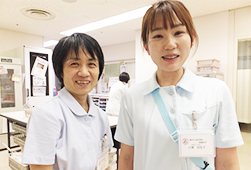薄い水色の制服を着た看護助手の2人が笑顔で並んでいる写真